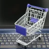 A mini shopping cart placed on a laptop keyboard, symbolizing online shopping and digital retail.
